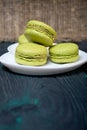 Light green macarons lie on a saucer. On pine planks with a crisp woody texture Royalty Free Stock Photo