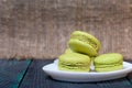 Light green macarons lie on a saucer. On pine planks with a crisp woody texture Royalty Free Stock Photo