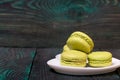 Light green macarons lie on a saucer. On pine planks with a crisp woody texture Royalty Free Stock Photo