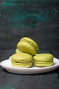 Light green macarons lie on a saucer. On pine planks with a crisp woody texture Royalty Free Stock Photo