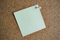 A light green paper note on a cork board, attached with a white pushpin. Copy space Royalty Free Stock Photo