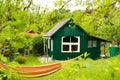 A light green small shed with white window frames, a gardenhouse in a beautiful wild garden with a colourful hammock in front of i Royalty Free Stock Photo