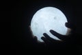 Light in hand. Person holding white light of ball lamp in hands on dark background. Magic light shine in the darkness concept.