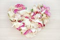 Light heart shape from pink and white rose and orchid petals on wooden background. Love and romance concept Royalty Free Stock Photo