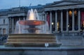 Light illuminates the water in one of the fountains at Trafalgar Square, Westminster, London, UK at dusk.