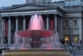 Light illuminates the water in one of the fountains at Trafalgar Square, Westminster, London, UK at dusk.