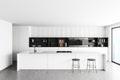 Light kitchen interior with bar countertop and seats near window, cooking area Royalty Free Stock Photo