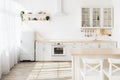 Light kitchen interior with white furniture and shelves, small refrigerator near window, empty space