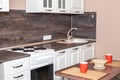 Light kitchen set with wooden worktop and sink, wooden table with crockery. Kitchen interior