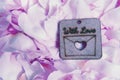 Light lavender dog-rose petals backround with waterdrops. Wooden heart shape nameplate on soft petal backround. Saint Valentine