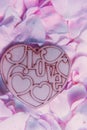 Light lavender dog-rose petals backround with waterdrops. Wooden heart shape nameplate on soft petal backround. Saint Valentine