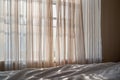 Light linen style textured curtains letting morning sunlight into a bedroom Royalty Free Stock Photo