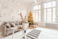 Light living room with Christmas tree. Comfortable sofa, high large Windows. Light white brick wall.