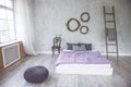 Light loft style bedroom interior,design made in gray and purple colors with modern furniture and windows,ladder next to white bed Royalty Free Stock Photo