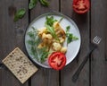 A light lunch of roasted cauliflower and halves of red tomato, a sprig of dill on a striped plate on an old wooden Royalty Free Stock Photo