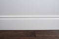 Light matte wall, white baseboard and tiles immitating hardwood flooring Royalty Free Stock Photo