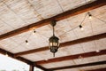 1-light metal chandelier under the ceiling made of bamboo and garland. Royalty Free Stock Photo