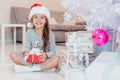 Light photo of cute kid sitting with gift in hands, like a little gnome in christmas decorated room.