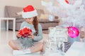 Light photo of cute kid sitting with gift in hands, like a little gnome in christmas decorated room. Royalty Free Stock Photo