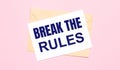 On a light pink background - a craft envelope. It has a white sheet of paper that says BREAK THE RULES Royalty Free Stock Photo