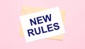 On a light pink background - a craft envelope. It has a white sheet of paper that says NEW RULES