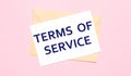 On a light pink background - a craft envelope. It has a white sheet of paper that says TERMS OF SERVICE Royalty Free Stock Photo