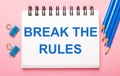 On a light pink background, light blue pencils, paper clips and a white notebook with the text BREAK THE RULES Royalty Free Stock Photo