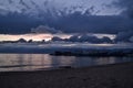 light pink sunset with blue dark clouds in sky in bay of lake Baikal with jetty mole pier with old ships and boats, evening Royalty Free Stock Photo