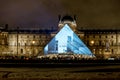 A light presentation displayed on a glass pyramid entrance of Louvre museum in the evening, Paris