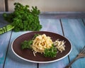 Finished pasta on a ceramic plate with sprigs of curly fresh parsley and a large bunch of parsley in the background