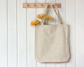 Light rag bag with flowers hangs on a white wooden wall Royalty Free Stock Photo