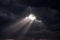 Beaming rays of light break through dark menacing clouds Royalty Free Stock Photo