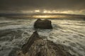 Light rays over the ocean waves splashing on rocks
