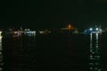 The light reflection of several goods ferries on the Amazon river, with the red lit bridge in the background during night time, at Royalty Free Stock Photo