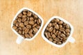 Light roast brown coffee beans in two white coffee cups