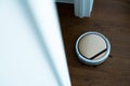 Light robot vacuum cleaner collects dust from parquet flooring moving along the floor