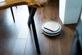 Light robot vacuum cleaner removes dust and dirt in an apartment on a wooden parquet