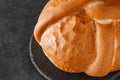 Light round loaf bread whole, with curlicues, on dark slate stone plate, selective focus