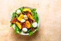 Light salad of fresh peaches, parma ham, mozzarella and green salad mix on peach colored background Royalty Free Stock Photo