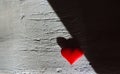 Light and shadow , dramatic effect,  red heart and old cement wall with rough deep cracks on stucco surface. Contrast textures of Royalty Free Stock Photo