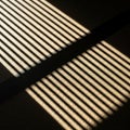 By sunlight filtering through window blinds, casting parallel lines Royalty Free Stock Photo