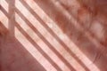 Light shines through a window, casting long shadows of bars onto a textured wall. The surface features a copper metallic gradient Royalty Free Stock Photo