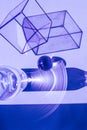 Light shining on a glass cube, water bottle, steel sphere, creating shadows