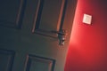 Light shining through open door in dark room with red wall. Mystery, success, hope concept Royalty Free Stock Photo