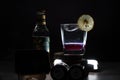 light shot on black background showing glass fileld with mulled infused wine gin with lemon wedge and bottle of tonic on