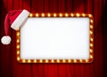 Light sign with red frame and Christmas Santa hat on theatre or cinema curtain Royalty Free Stock Photo