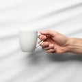 Light skin tone holds a white ceramic mug by the handle. The Royalty Free Stock Photo