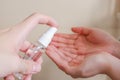 Light-skinned Asian woman pumping a hand sanitizer spray bottle to another hand. Royalty Free Stock Photo