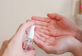 Light-skinned Asian woman pumping a hand sanitizer spray bottle to another hand. Royalty Free Stock Photo