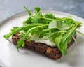 Light snack, sandwich with curd cheese and fresh arugula on a small plate